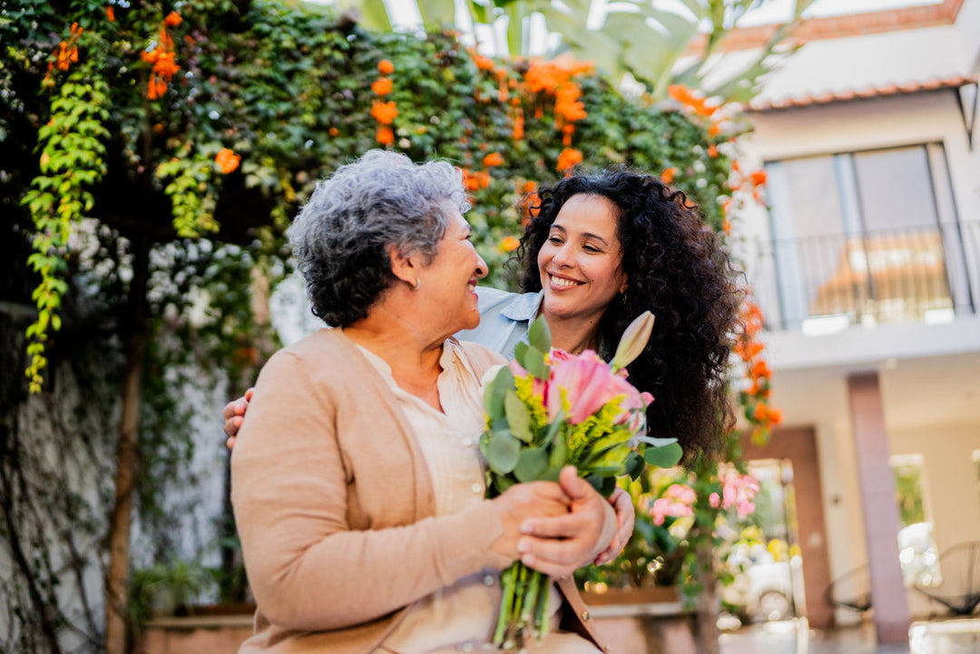 Mother and doughter smiling at each other as the mother is getting flower for mother's day.
