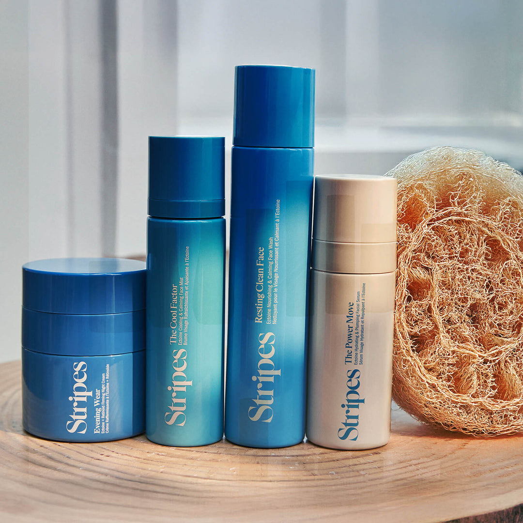 Nighttime Skincare Routine bundle with Stripes cleanser, serum, cream, and cooling mist on wooden surface with loofah.