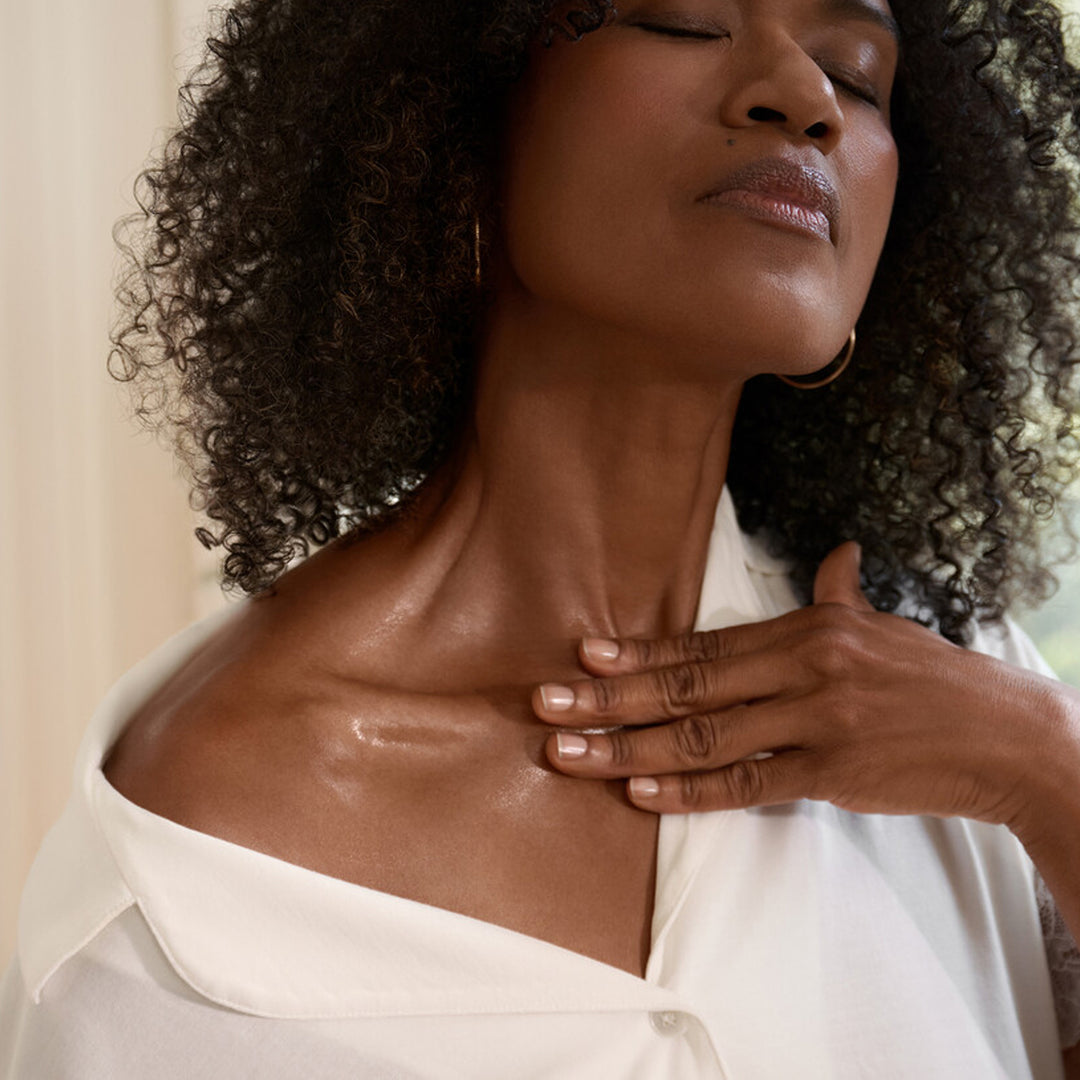 Black female model showing her shiny neck wearing a white blouse