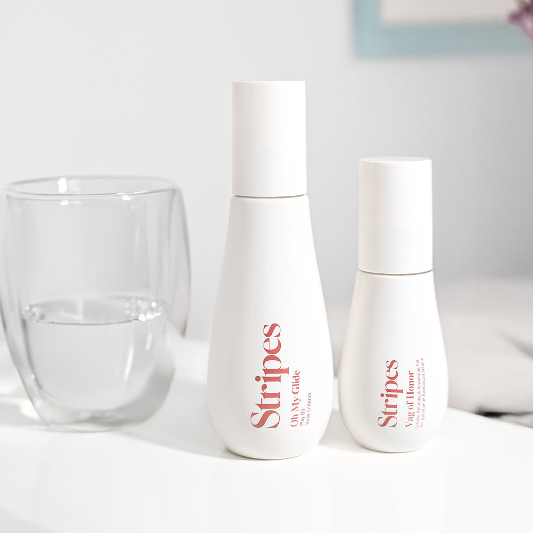 Oh My Glide and Vag of Honor bottles labeled 'Stripes' on a white surface with a glass of water.