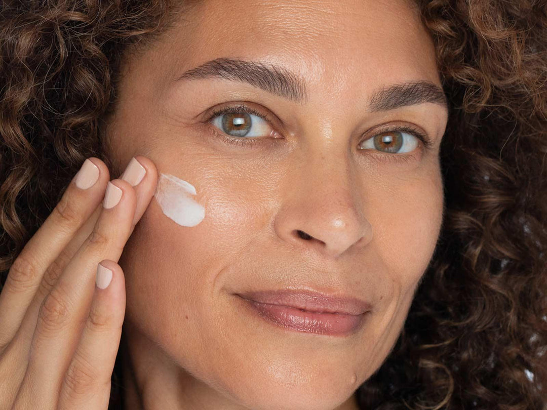 Evening Wear night cream applied by woman, hydrating and firming skin for a radiant, youthful complexion.