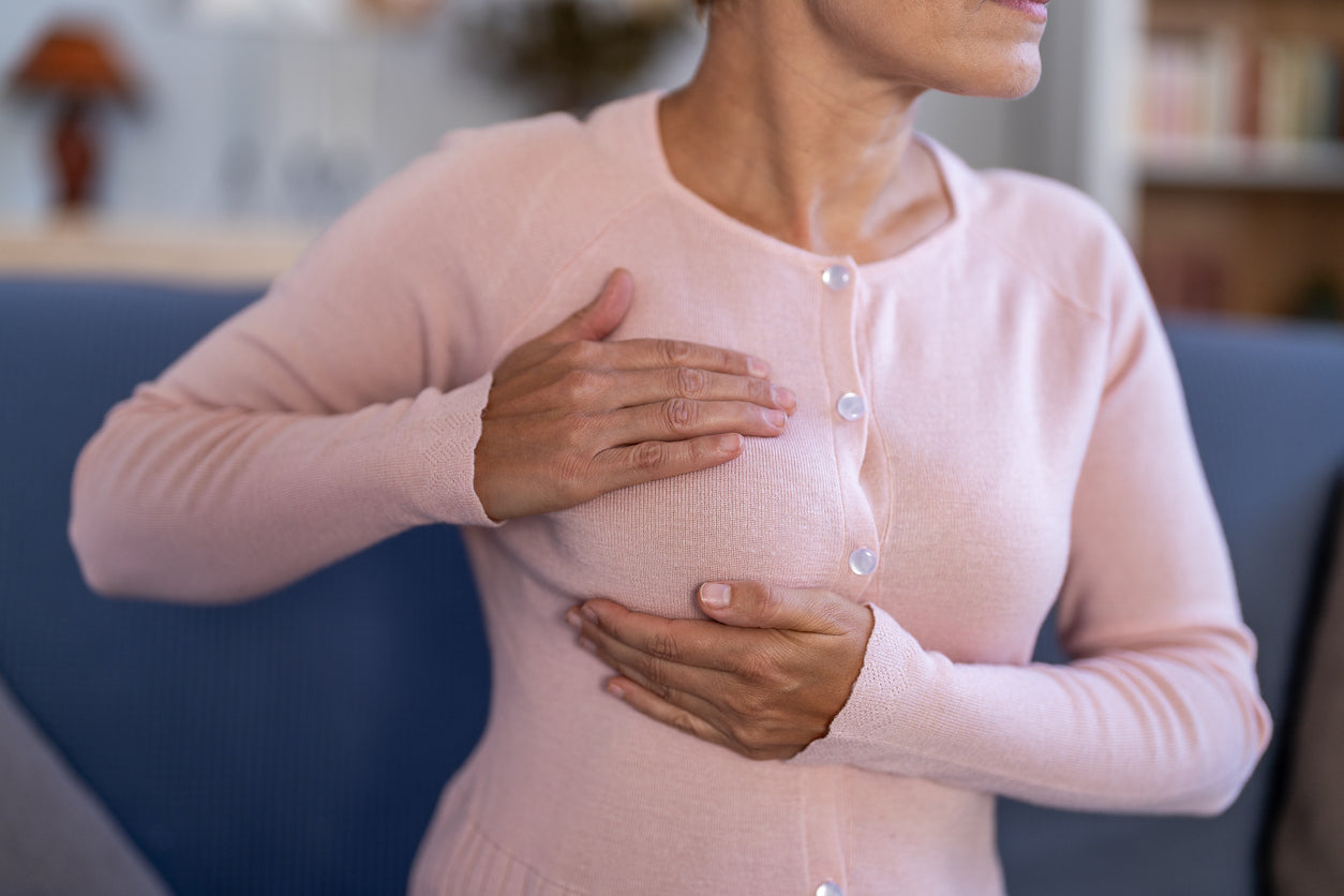 Woman wearing a pink sweater with pearl buttons, standing indoors.