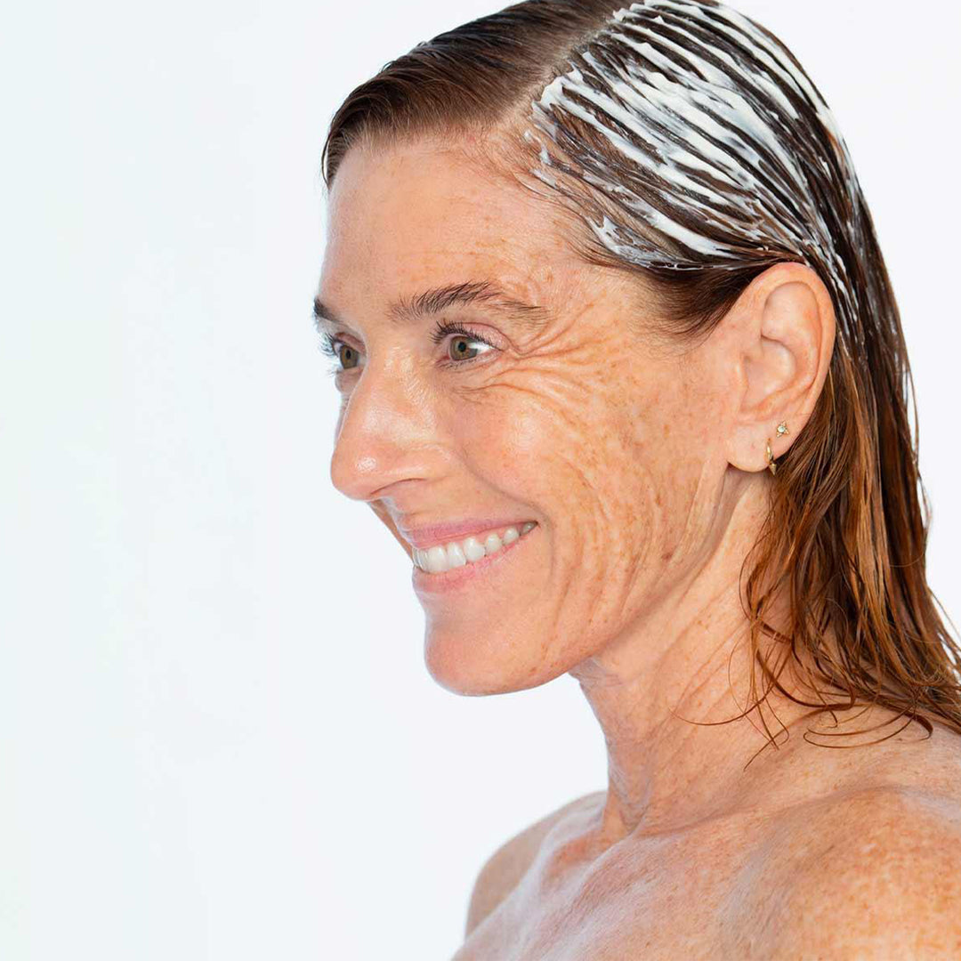 Woman with soap suds in her hair against a white background