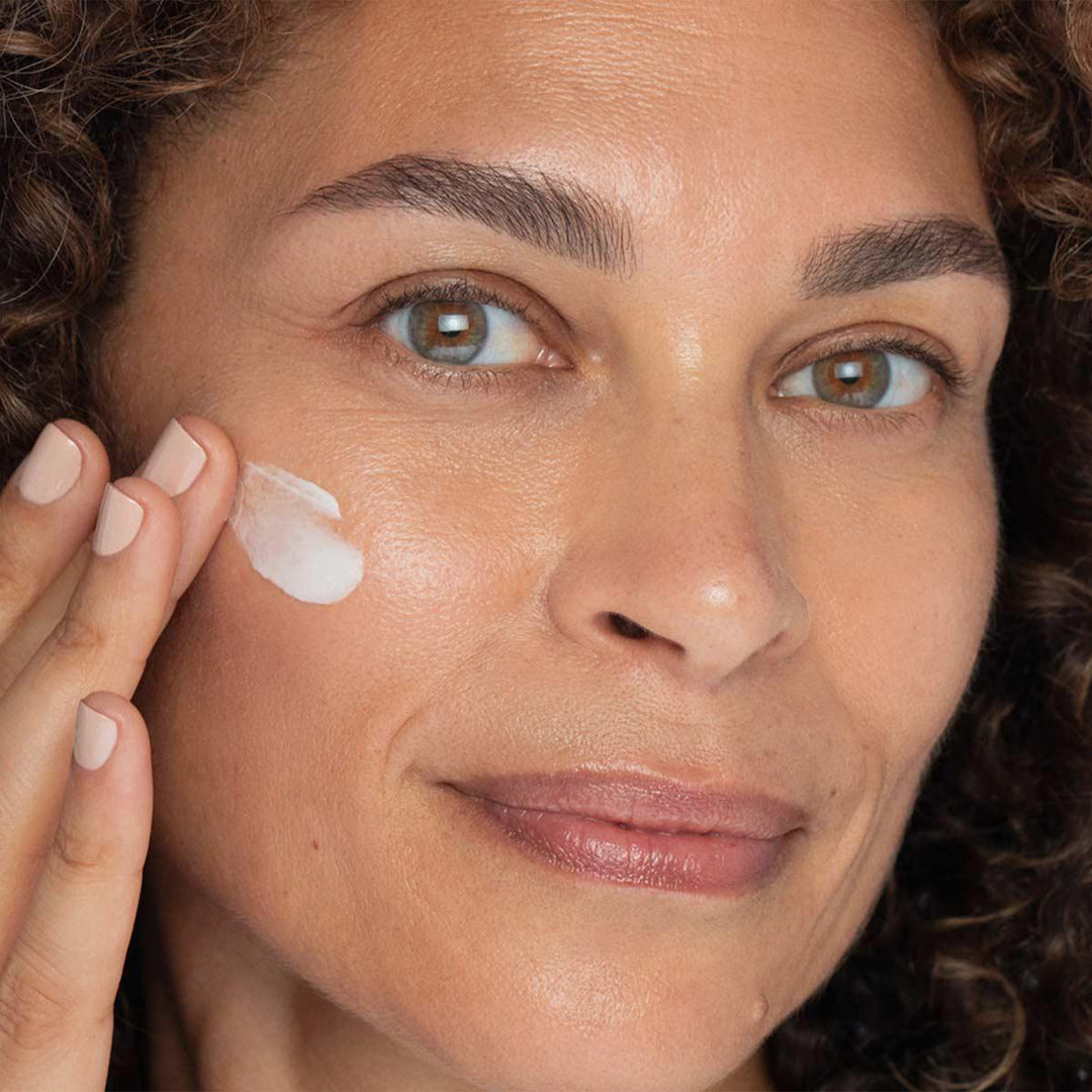 Woman applying cream to her face with a close-up view.