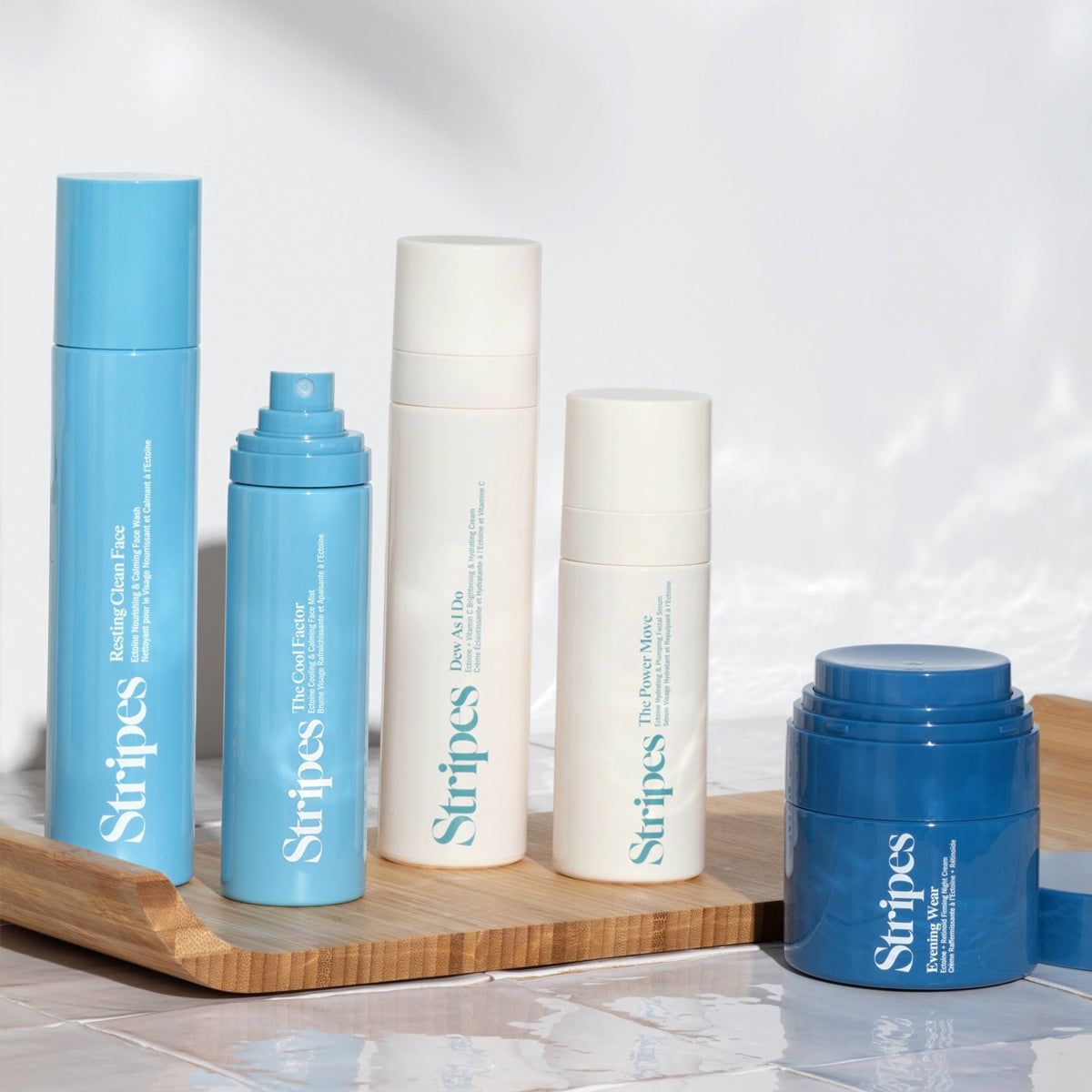 Set of Stripes skincare products on a wooden tray with a light background